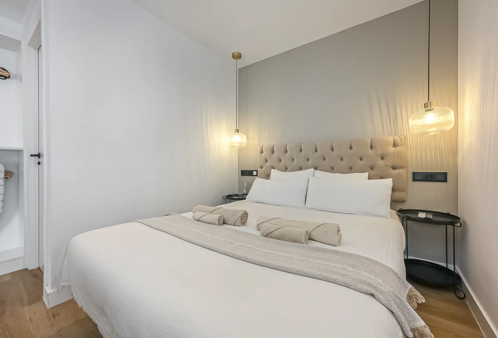 The Signature Suite: a double bed with a tufted headboard against a grey wall, a brass pendant hanging on either side
