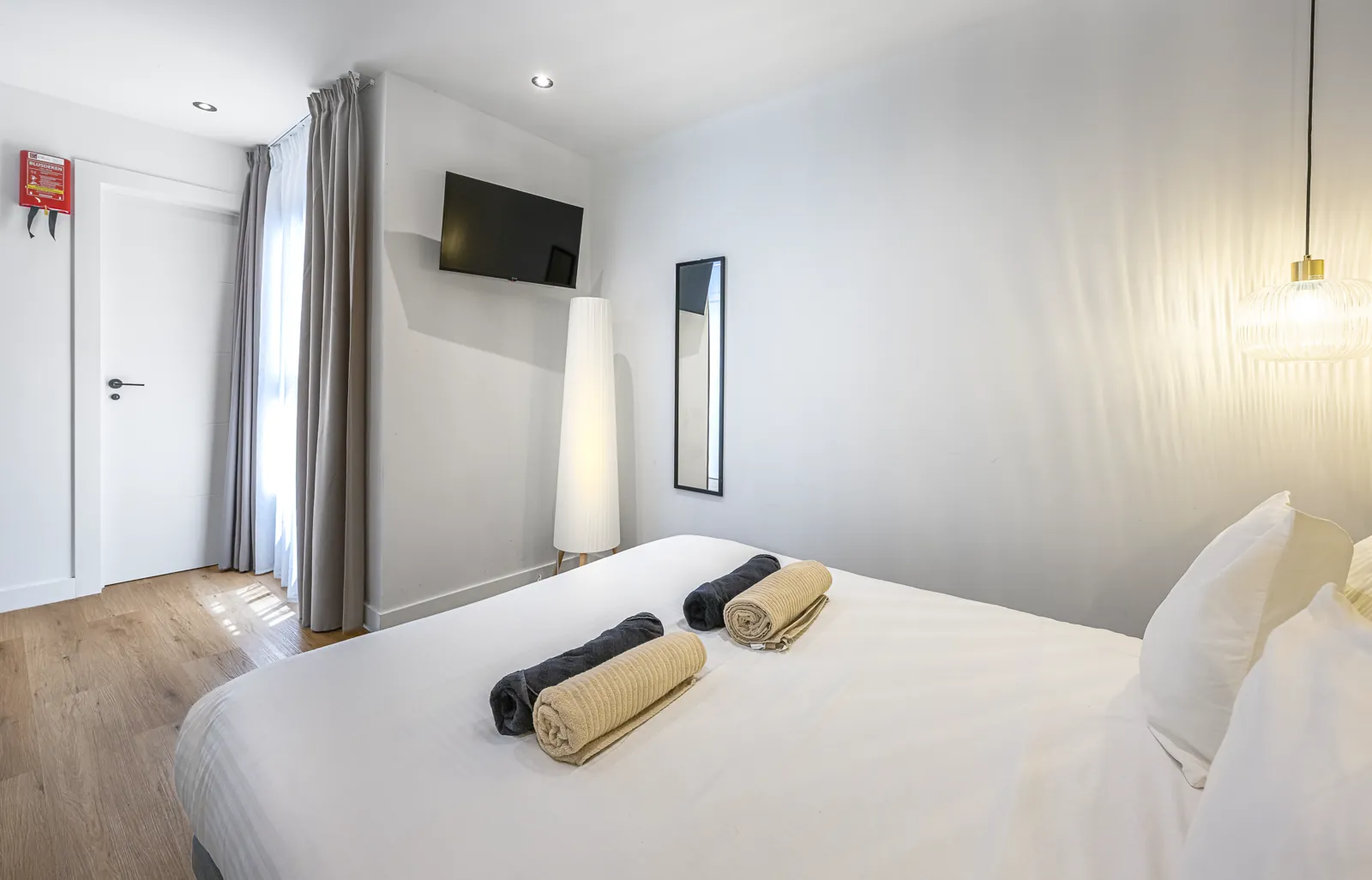Room 2 from the bed: the television, a floor lamp and the curtained window, with a pendant overhead