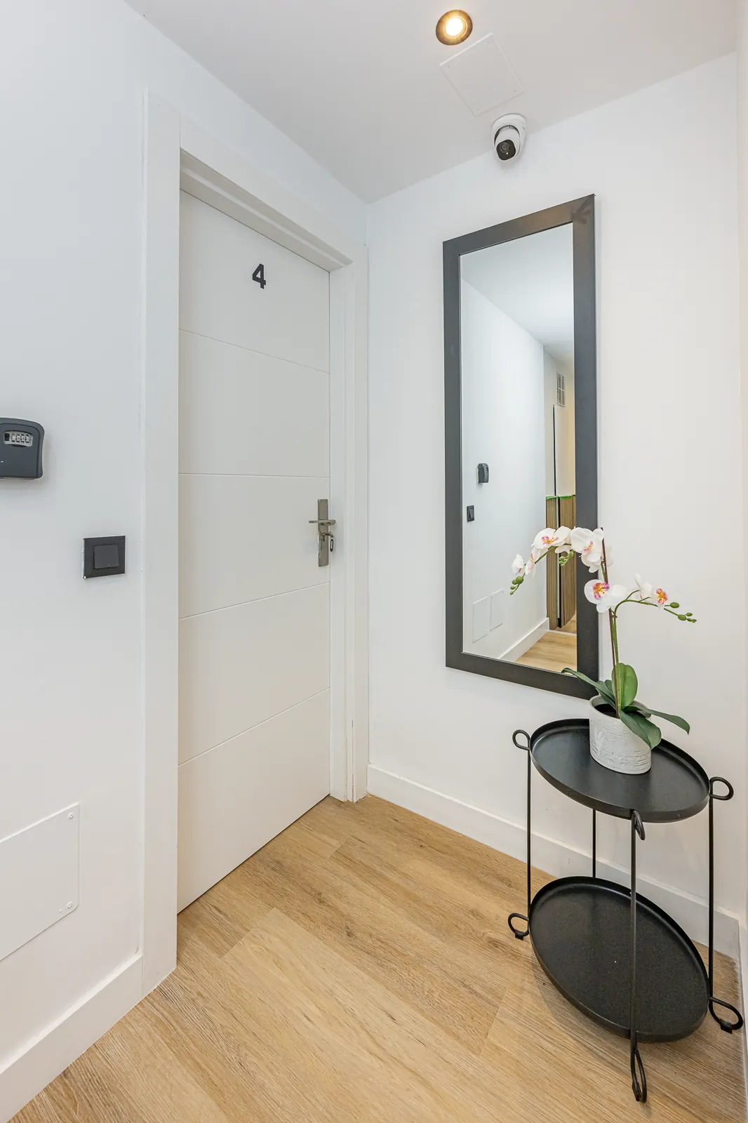 The landing outside Room 4: a long black framed mirror, an orchid on a side table, and the door marked 4