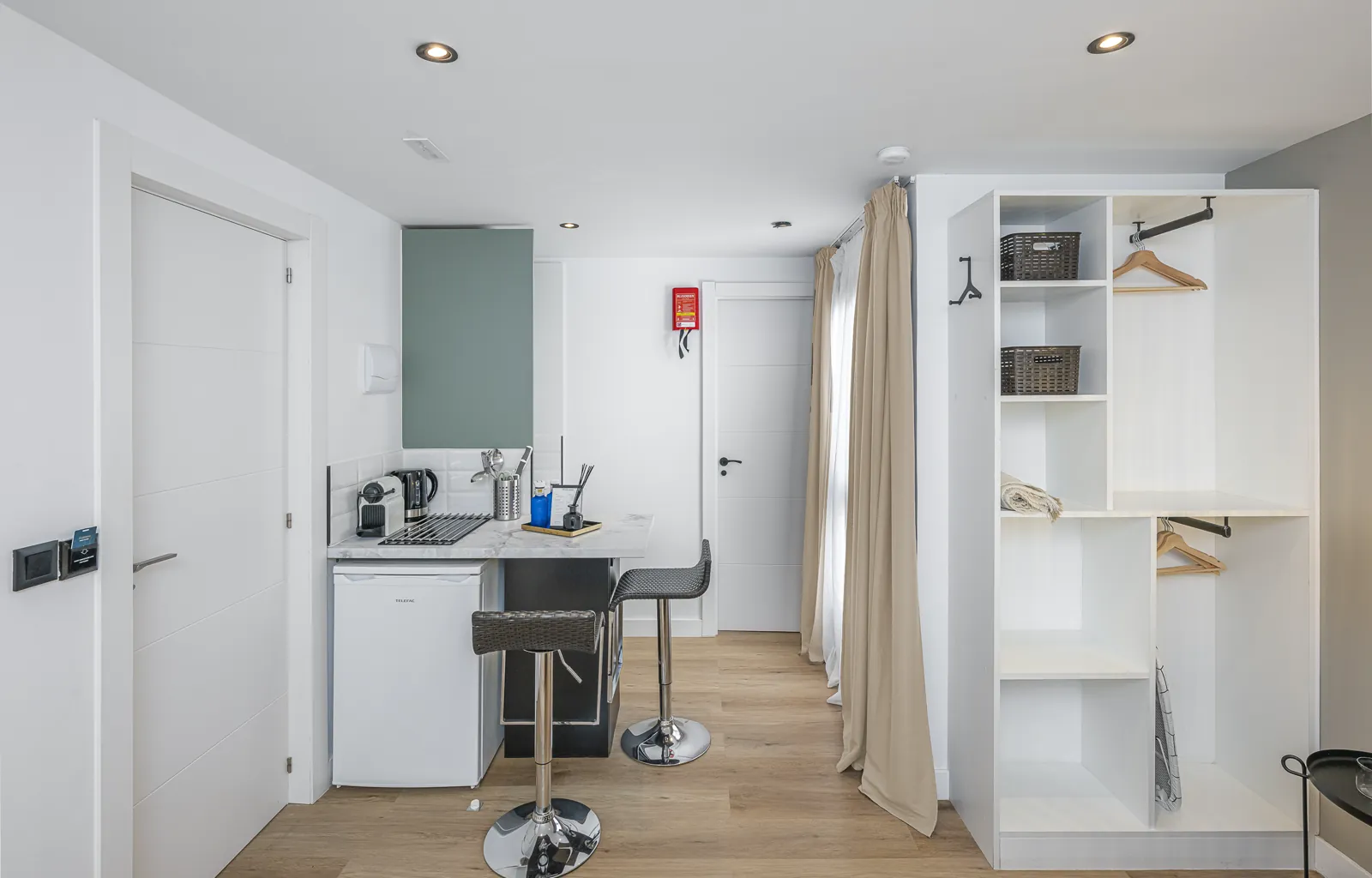 Room 4: the kitchenette and its bar with two stools, and the open shelving beside the window