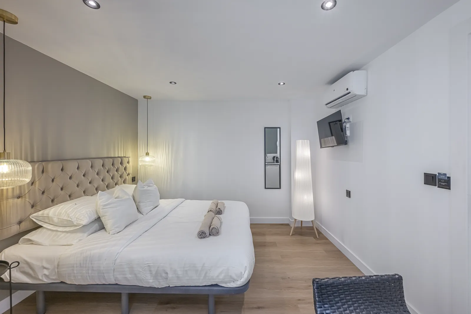 Room 4 from the corner: the tufted headboard, the television and the floor lamp along the far wall