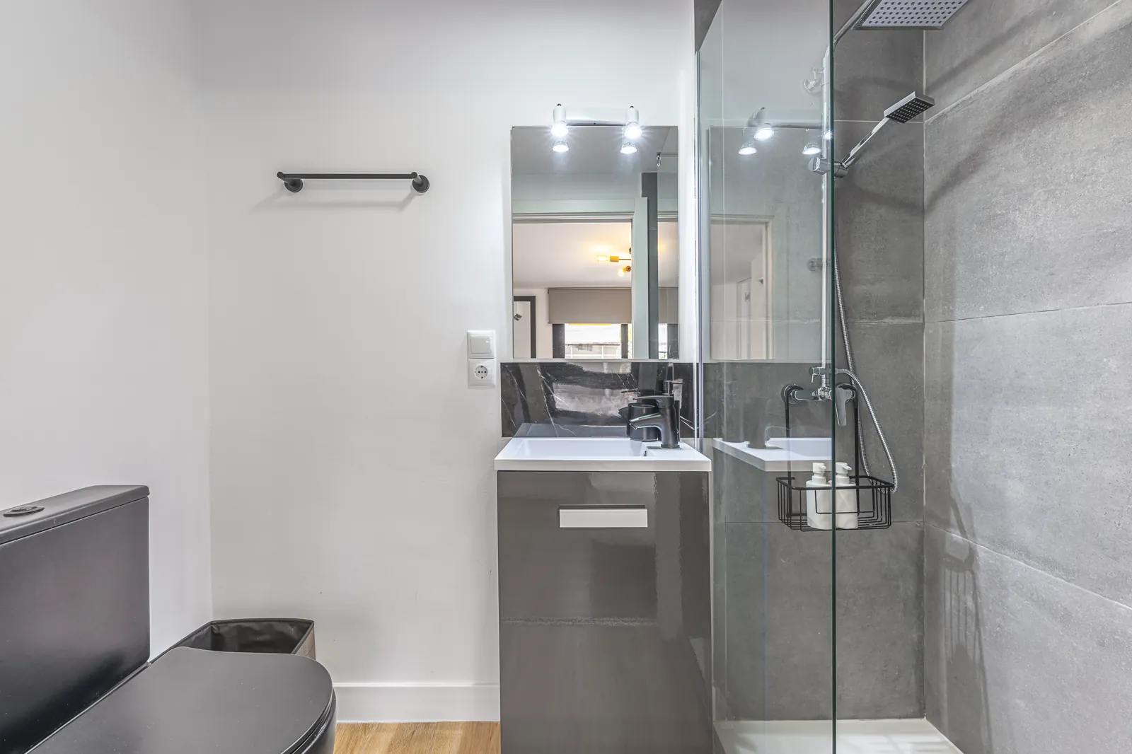Room 5: the shower room in grey tile, a basin under a long mirror beside the glass walk-in shower